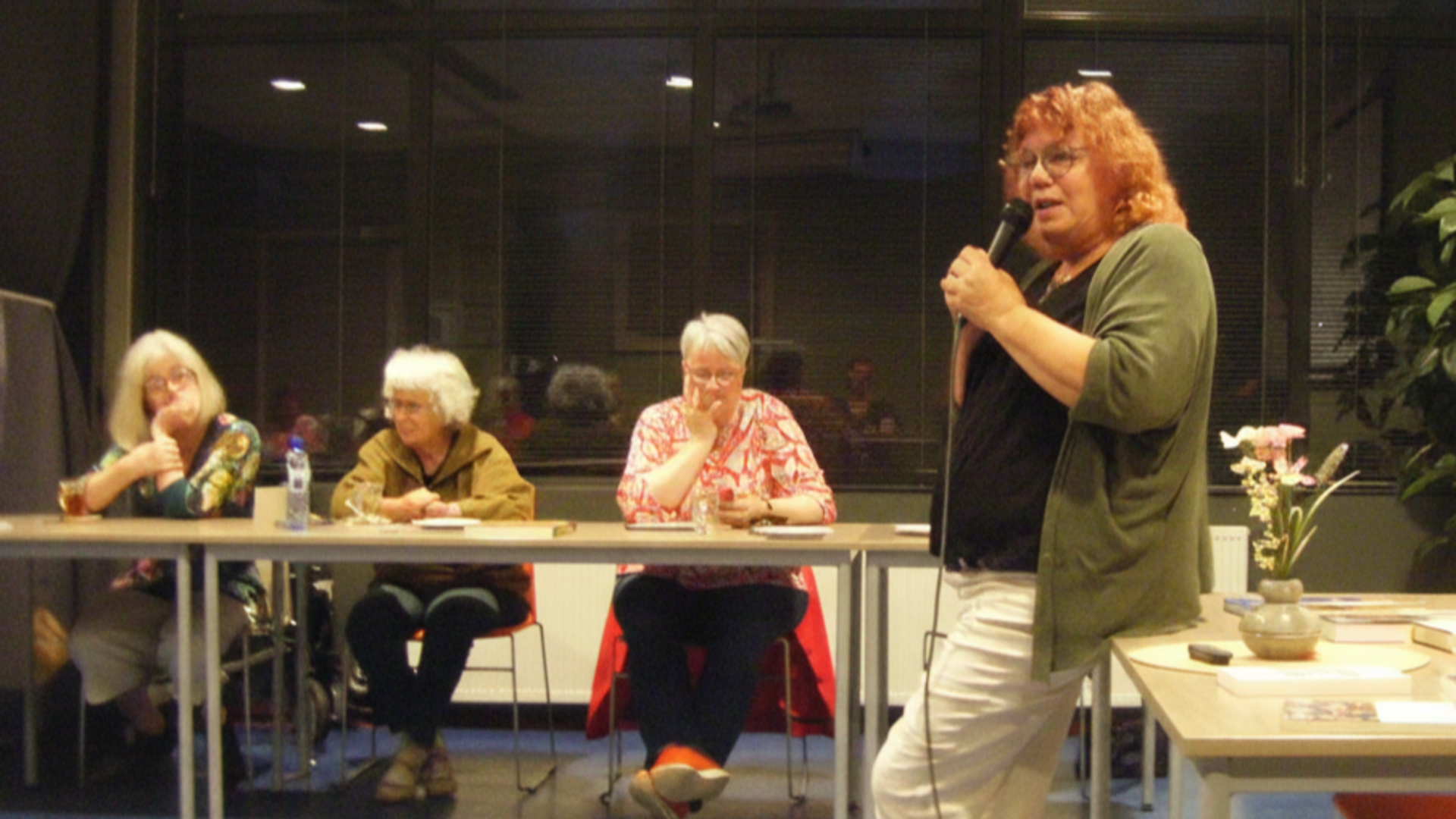 Ria Haan aan het woord, 3 vrouwen zittend aan een tafel luisteren.